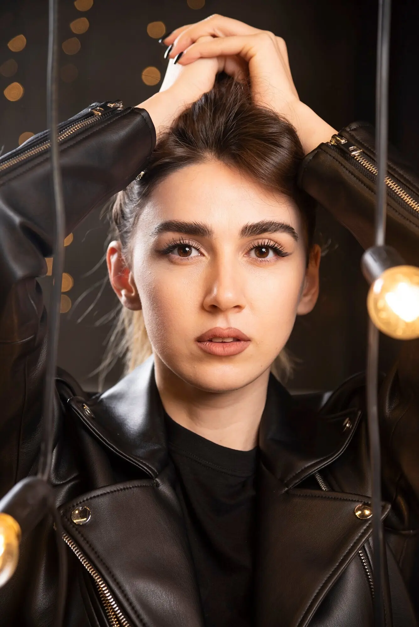 Porträt eines attraktiven jungen Models in schwarzer Lederjacke, das neben Lampen posiert.